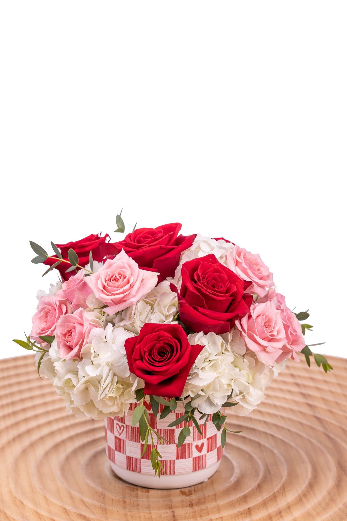 Check Yes features red roses, pink spray roses, and white hydrangea with greenery arranged in a red-and-white checked ceramic vase.