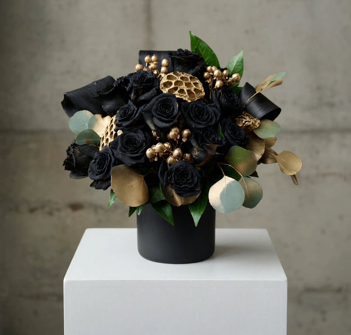 Fifteen black-tinted roses with hypericum berries arranged in a black ceramic container