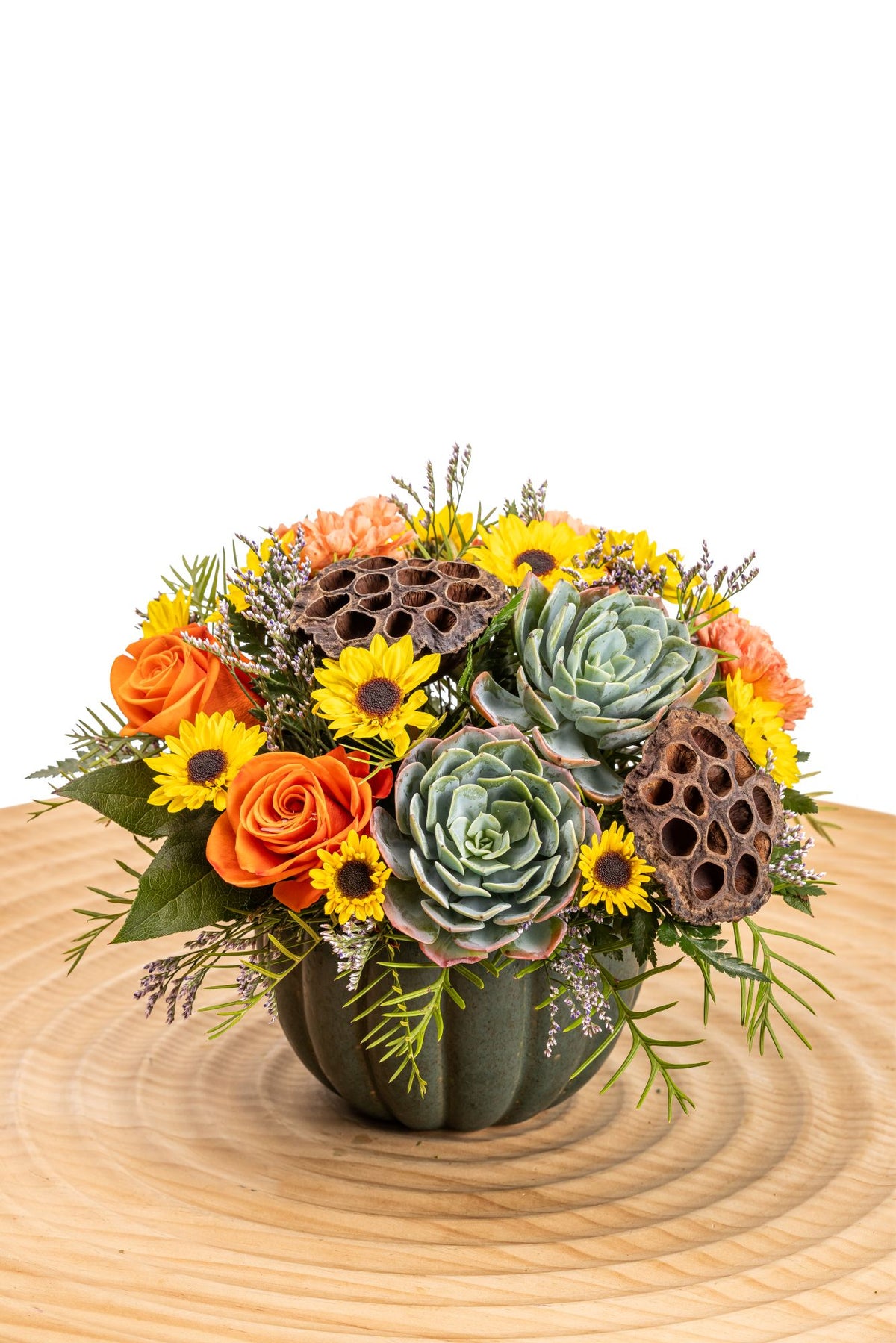 Chic Pumpkin in a sage-green ceramic pumpkin container, features orange roses, orange carnations, and Viking poms, accented with succulents, lotus pods, limonium, and lush greenery.