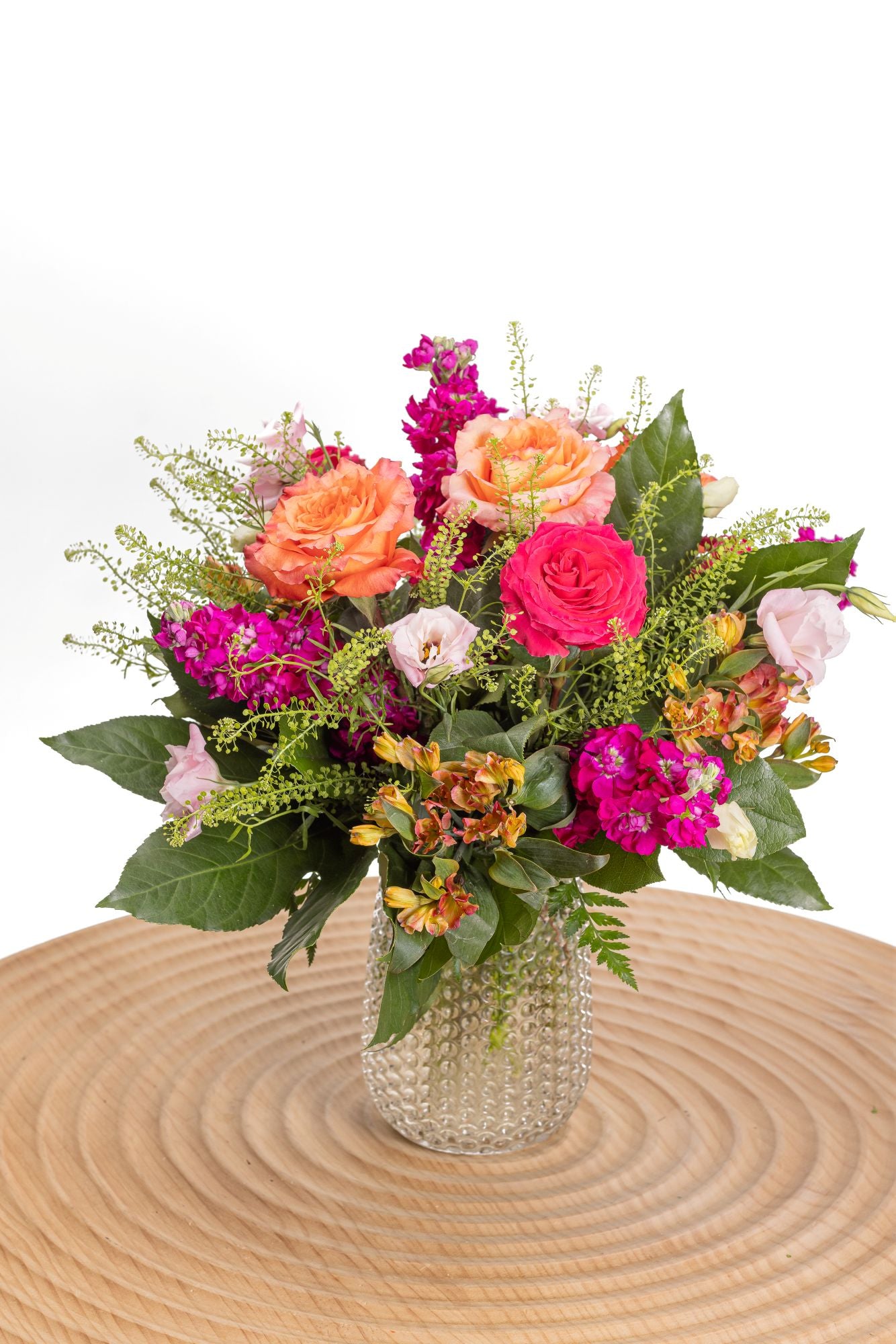 Hugs and Kisses features Free Spirit roses, hot pink roses, lisianthus, alstroemeria and purple stock in a glass posie vase.