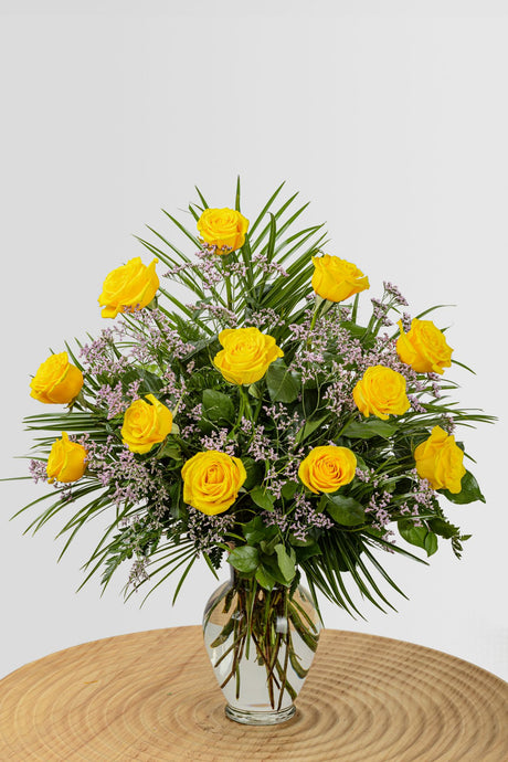 One dozen ultimate yellow roses with greenery.